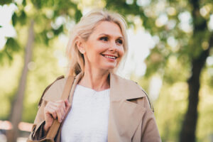 Smiling mature woman outdoors representing non-invasive facelift treatments for natural facial rejuvenation.