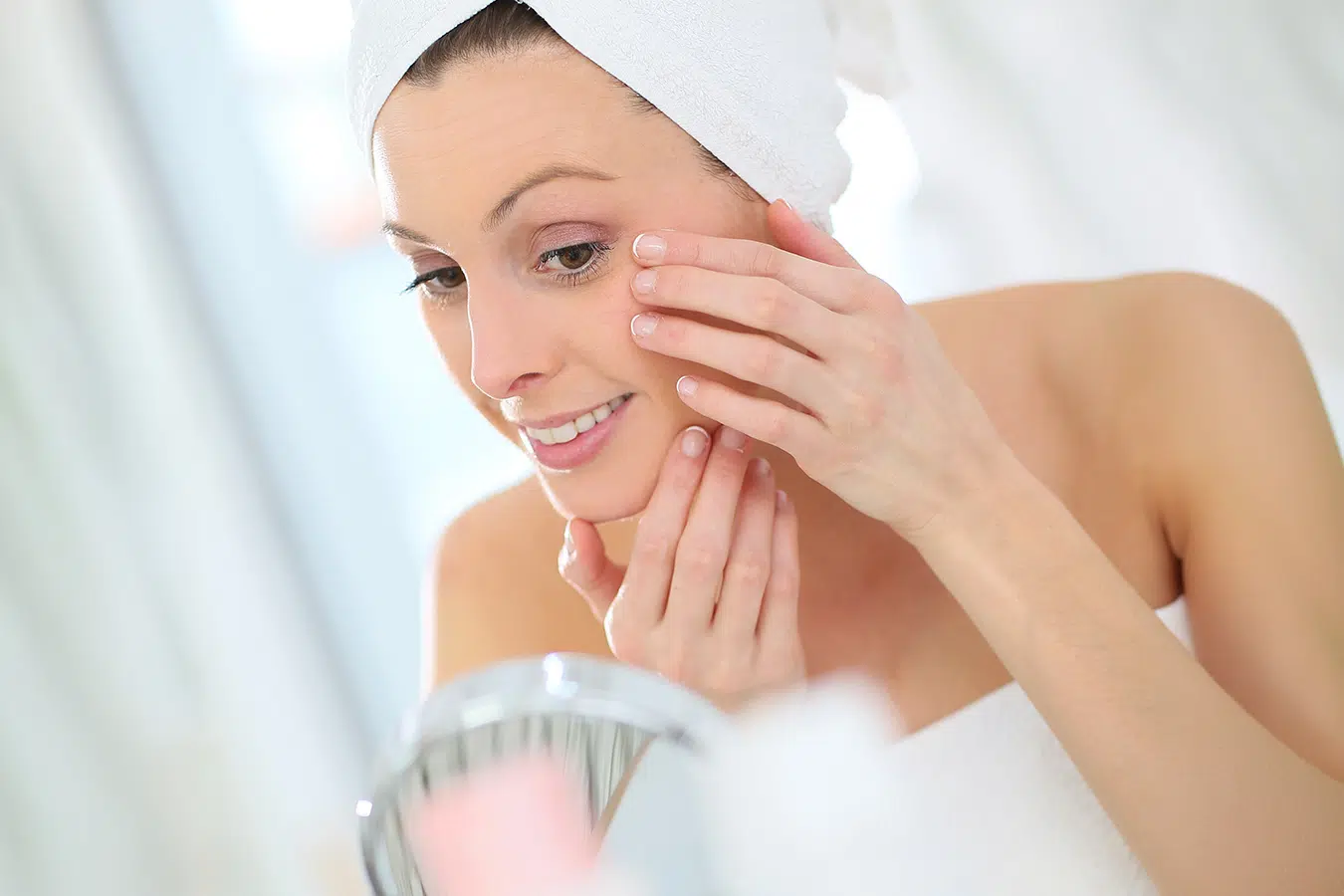 Woman examining her skin in a mirror representing laser scar treatment and complexion restoration.