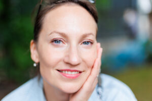 Smiling woman representing Sculptra treatment for facial volume restoration without facelift surgery.
