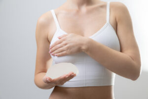 Woman holding breast implant representing candidacy for breast augmentation and personalized implant planning.