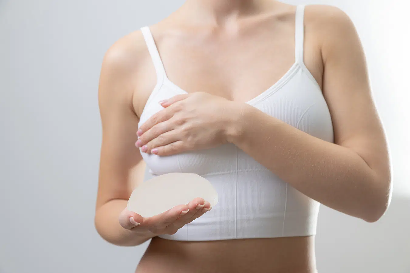 Woman holding breast implant representing candidacy for breast augmentation and personalized implant planning.