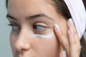 Woman applying eye cream representing non-surgical eye care for a refreshed, youthful appearance.