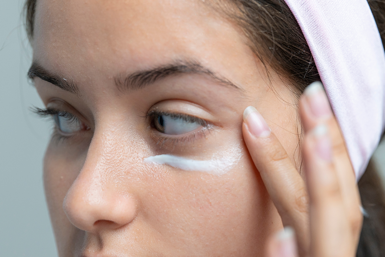 Woman applying eye cream representing non-surgical eye care for a refreshed, youthful appearance.