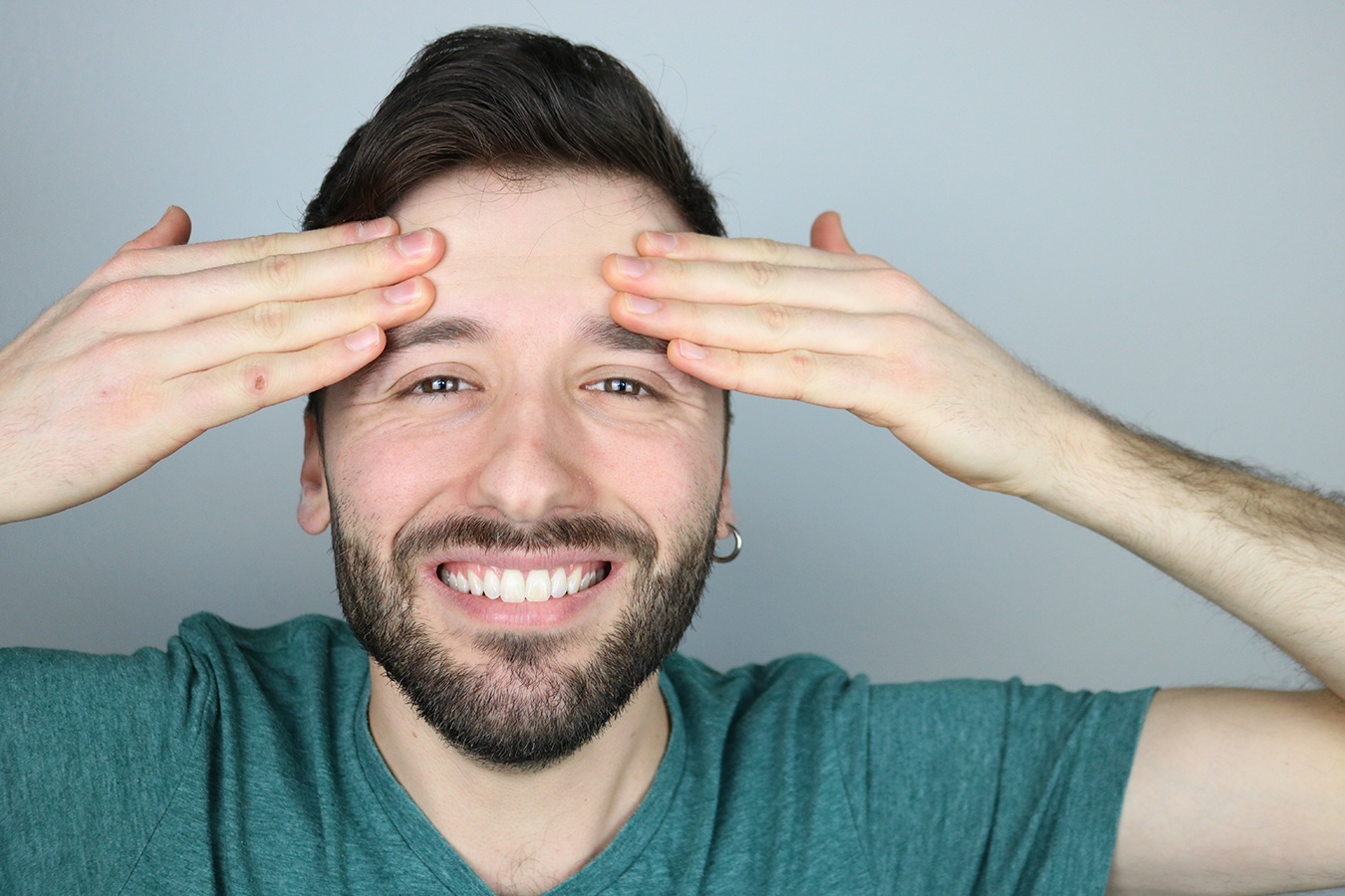 Smiling man touching forehead representing Bro-Tox treatments for men’s wrinkles and aging well.