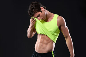 Athletic man lifting shirt representing Botox treatment for excessive sweating in the underarms.