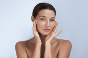 Woman touching her face, representing natural lip filler treatment for fuller lips.