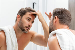 Man checking his chin in the mirror before Kybella treatment for double chin fat.