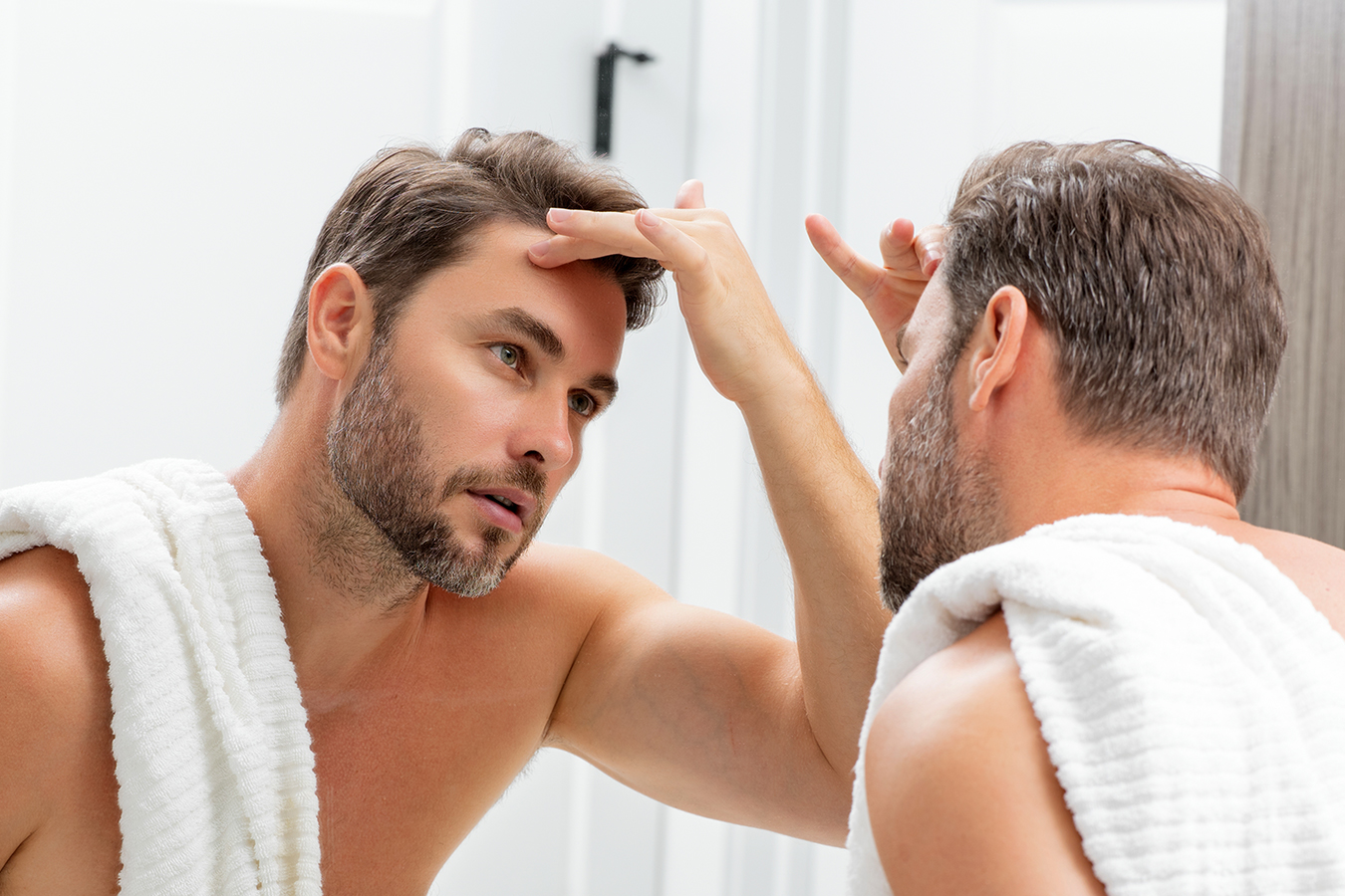 Man checking his chin in the mirror before Kybella treatment for double chin fat.