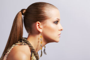 Woman wearing earrings, highlighting earlobes for sagging earlobe injection treatment.