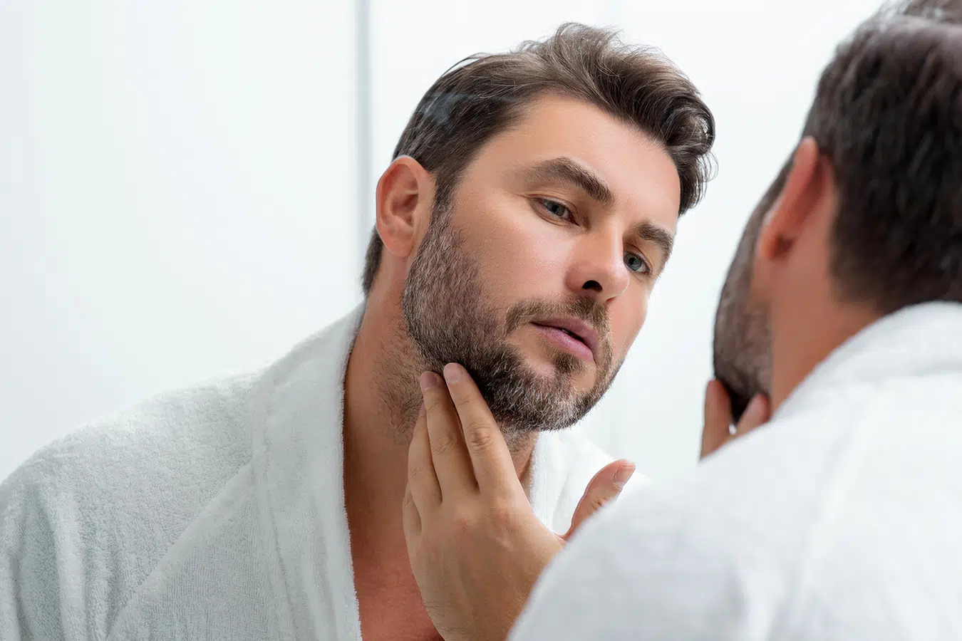 Man checking chin area in mirror for Kybella chin fat treatment information