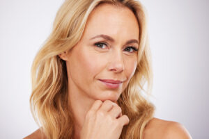 Woman touching chin for Kybella treatment and double chin reduction information.