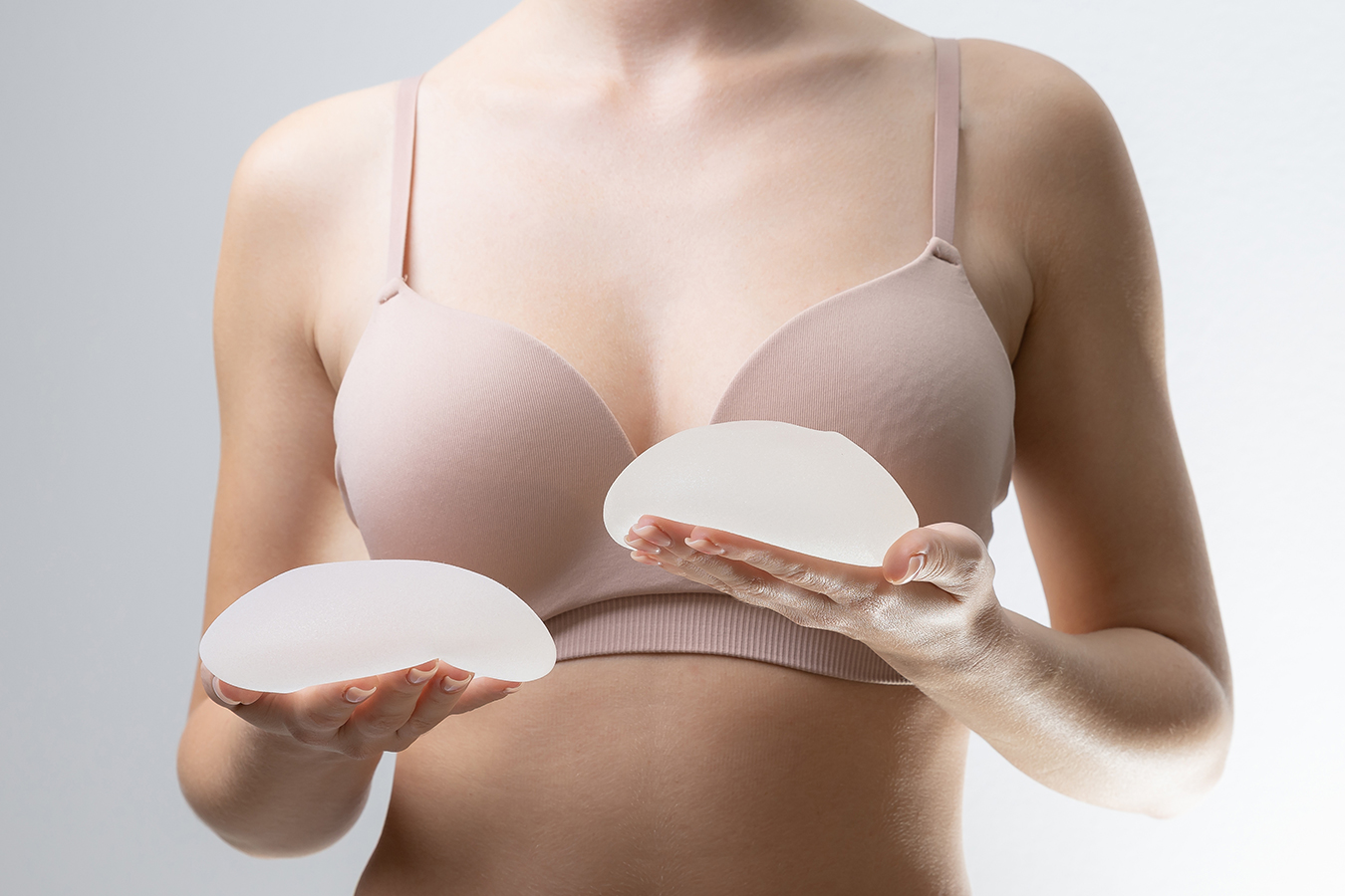 Person holding implants for breast augmentation implant size and body type planning.