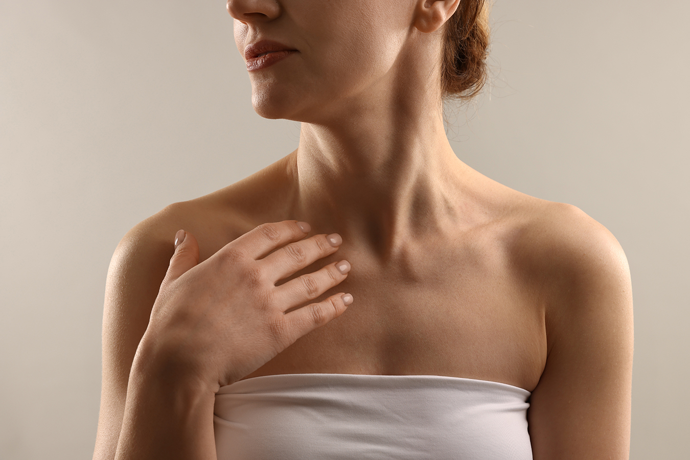 Woman touching neck for neck lift surgery and loose skin treatment information