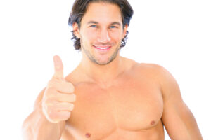 Smiling shirtless man giving a thumbs-up while discussing gynecomastia and man boobs treatment options.