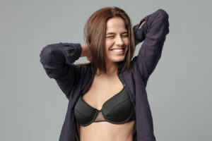Smiling woman in a black bra representing confidence and readiness for breast augmentation.