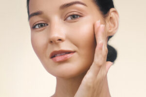 Woman touching her jawline, highlighting Kybella treatment for reducing double chin fat.