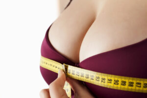 Woman measuring her bust, representing discreet breast augmentation scar placement beneath the breast or around the areola.