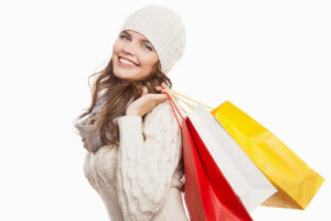 Smiling woman carrying shopping bags, representing early planning for holiday cosmetic treatments.