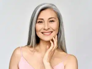 Smiling woman in her 50s with smooth, radiant skin, representing the benefits of aesthetic procedures to address aging concerns like collagen loss.