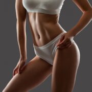 Woman showing toned midsection and thighs after liposuction under local anesthesia.