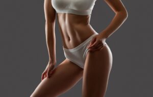 Woman showing toned midsection and thighs after liposuction under local anesthesia.