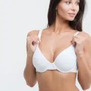 Confident woman in white bra with proportional breasts after augmentation, emphasizing natural results without rippling