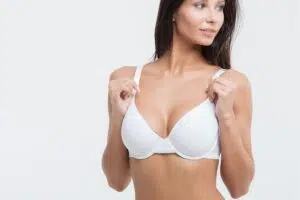 Confident woman in white bra with proportional breasts after augmentation, emphasizing natural results without rippling