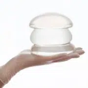 Gloved hand holding silicone breast implants, representing reasons and timing for breast implant exchange surgery.