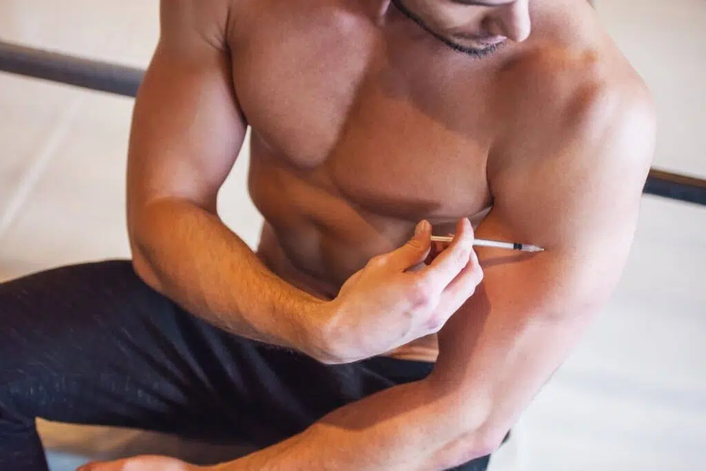 Man self-injecting testosterone, illustrating how anabolic steroids may contribute to gynecomastia and hormonal imbalance