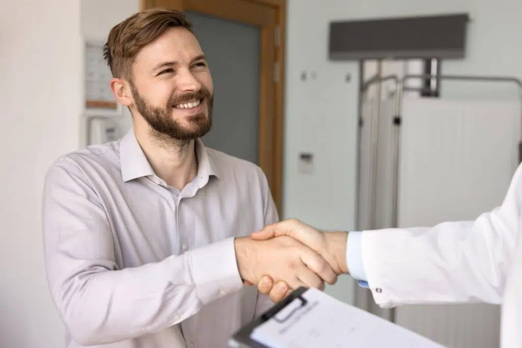 Male patient shaking hands with doctor during gynecomastia consultation and recovery planning discussion