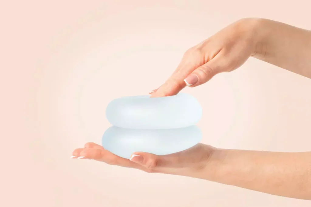 Hands holding two breast implants.