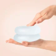 Hands holding two breast implants.