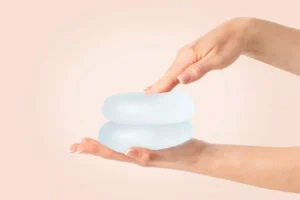 Hands holding two breast implants.