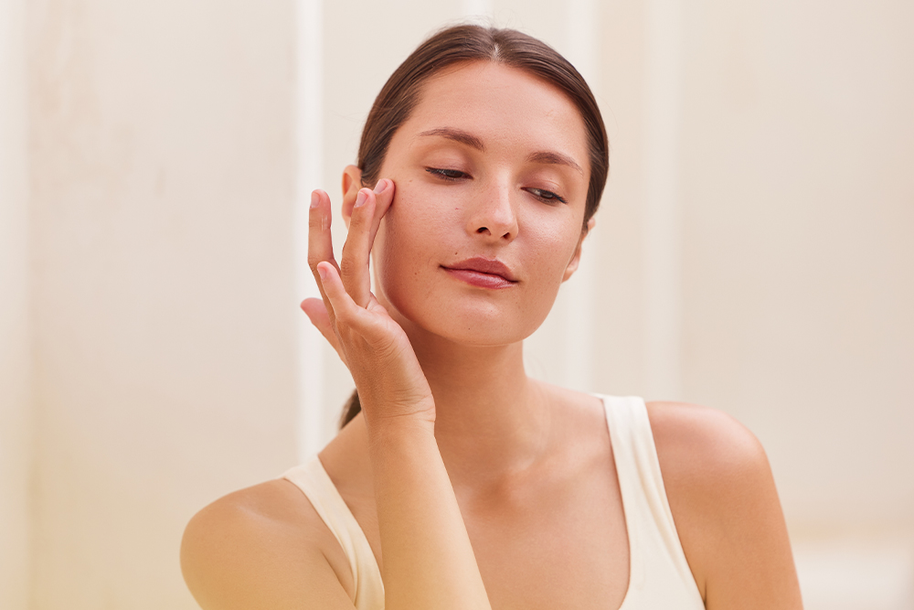 Woman touching her cheek, representing a personalized physician-guided skin care plan in Boston, MA.